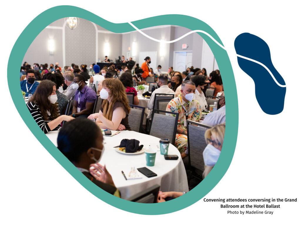 A large organic shape with a green background and a picture of a large room full of convening participants. A navy organic shape is on the upper right-hand corner.