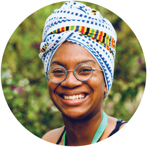 Headshot for Chi-Ante "Chi" Jones. Chi wears a colorful headwrap, blue rim circular glasses, a green lanyard, and a black thin strapped tank top.