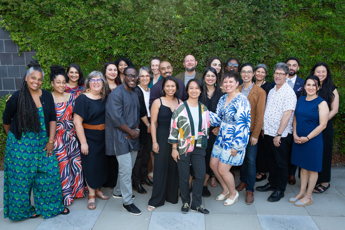 NFG staff and board pose for a group photo in front of a brick wall covered in greenery.